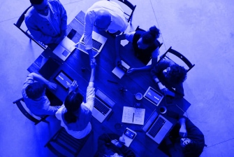Small business team working together during a meeting, with laptops, notes, and a handshake above the desk
