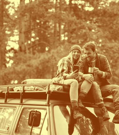 a couple sitting on the roof of a vehicle