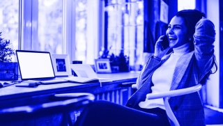 Remote worker at desk on phone looking happy
