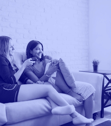 two women sitting on the sofa watching tv